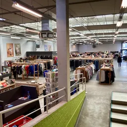 Overzicht van de winkelvloer met rekken kleding, stellingen en winkelafdelingen onder fluorescente verlichting