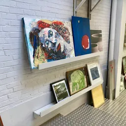 Wandplankjes met kunstwerken, schilderijen en decoratieve items in een kringloopwinkel