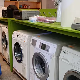 Witgoedafdeling met verschillende wasmachines en droogkasten onder groen stellingwerk