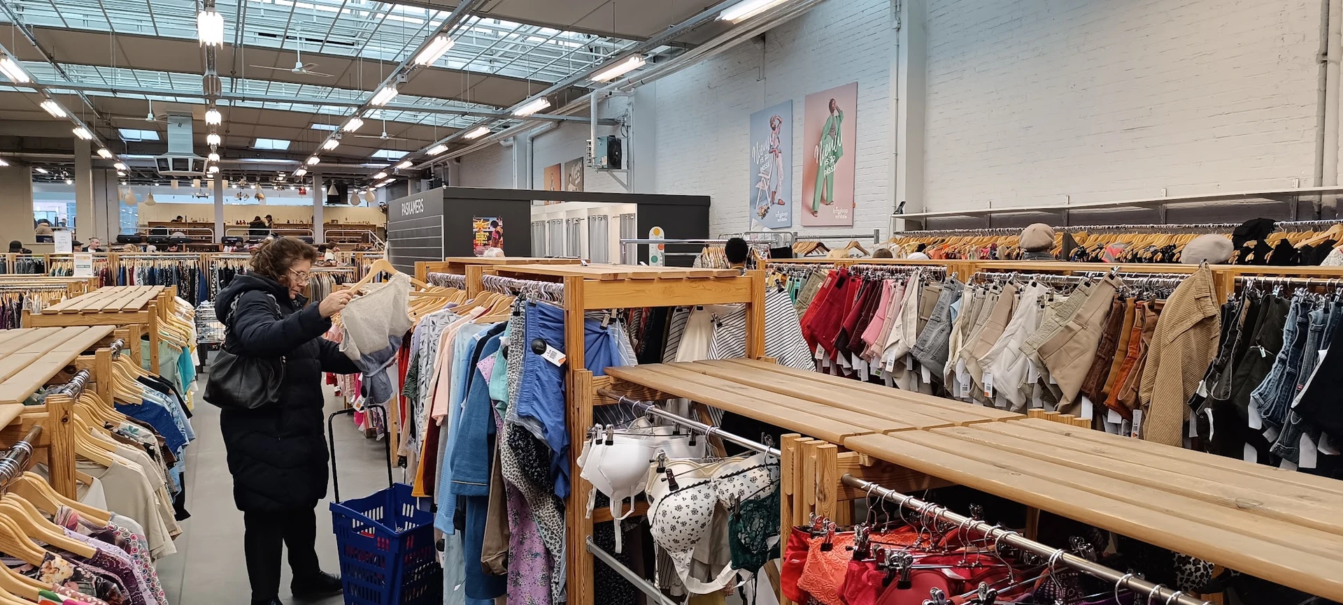 Houten rekken met tweedehands kleding, kinderkleding en textiel netjes uitgestald in de winkel