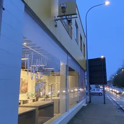 Gevelfront van kringloopwinkel met verlichte etalage aan schemering, winkelramen en ingang zichtbaar