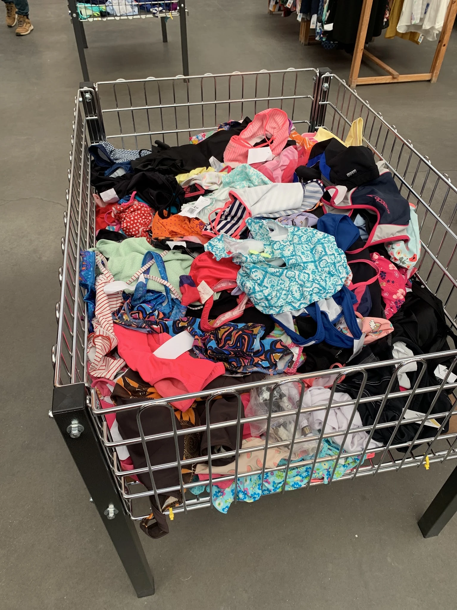 Winkelwagen vol met diverse tweedehands kinderkleding in verschillende kleuren en patronen