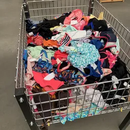 Winkelwagen vol met diverse tweedehands kinderkleding in verschillende kleuren en patronen