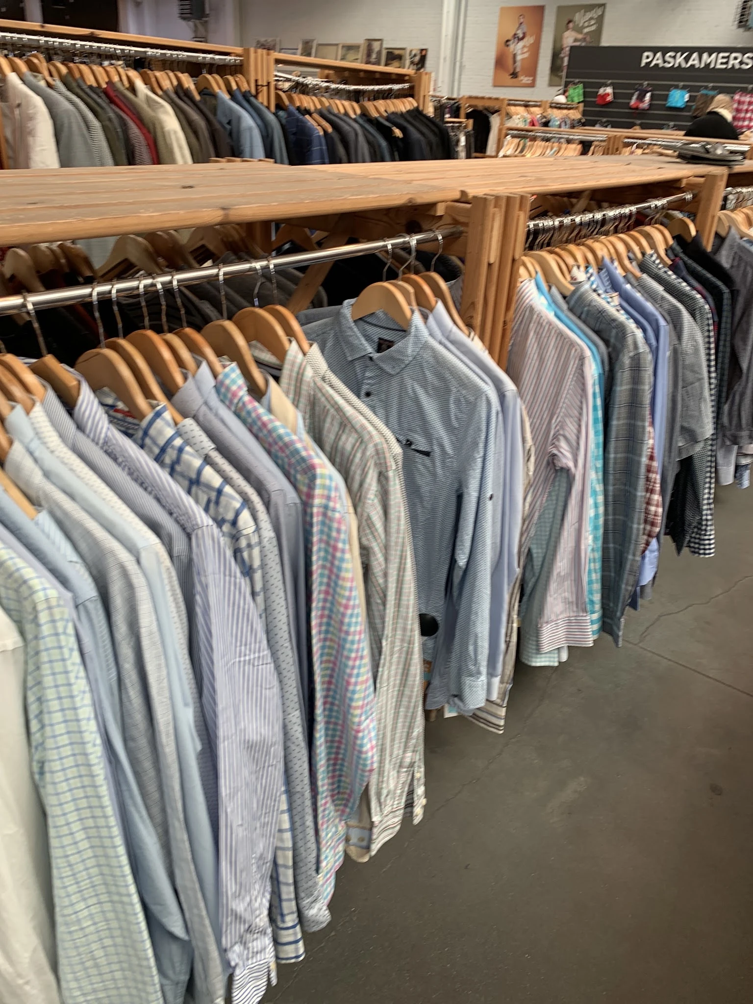 Rekken met tweedehands herenshirts en overhemden op houten hangers