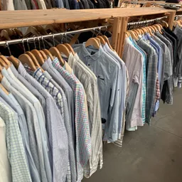 Rekken met tweedehands herenshirts en overhemden op houten hangers