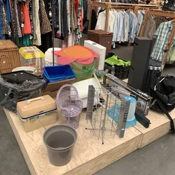 Tafel vol huishoudelijke artikelen: ventilator, bakjes, dienblad, schoonmaakmiddelen en ander tweedehands spullen