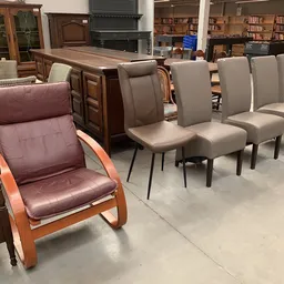 Groep grijze stoelen en een bruinrode fauteuil met houten frame in showroom