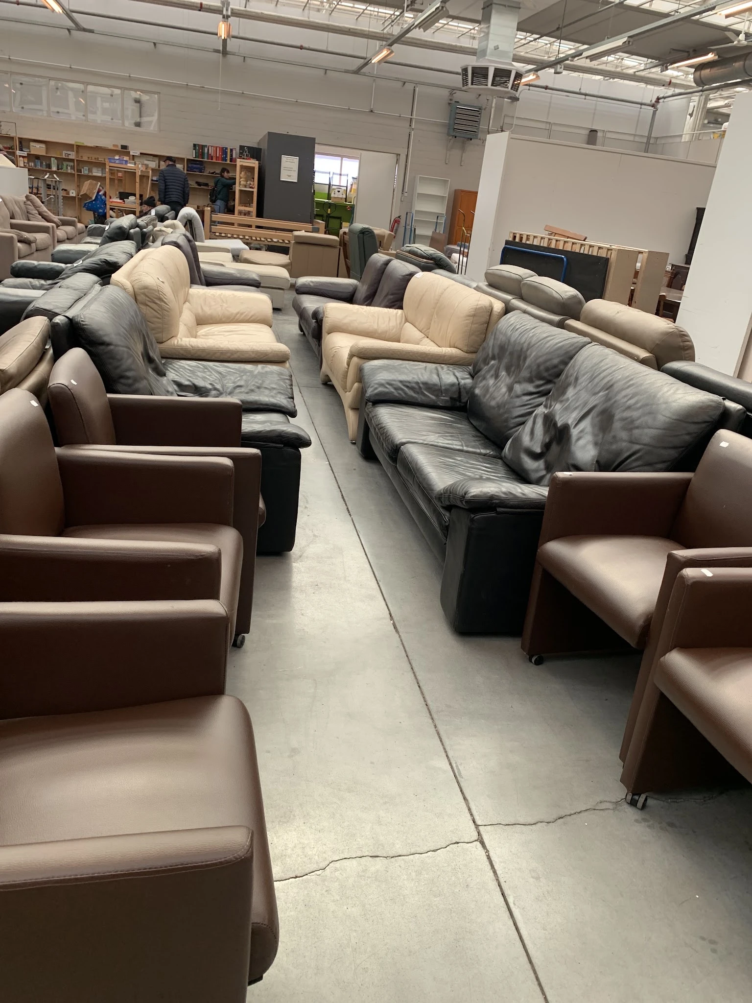 Diverse tweedehands fauteuils en stoelen in verschillende kleuren en stijlen uitgestald in de winkel