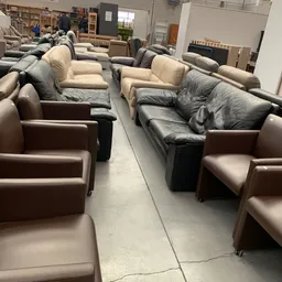 Diverse tweedehands fauteuils en stoelen in verschillende kleuren en stijlen uitgestald in de winkel