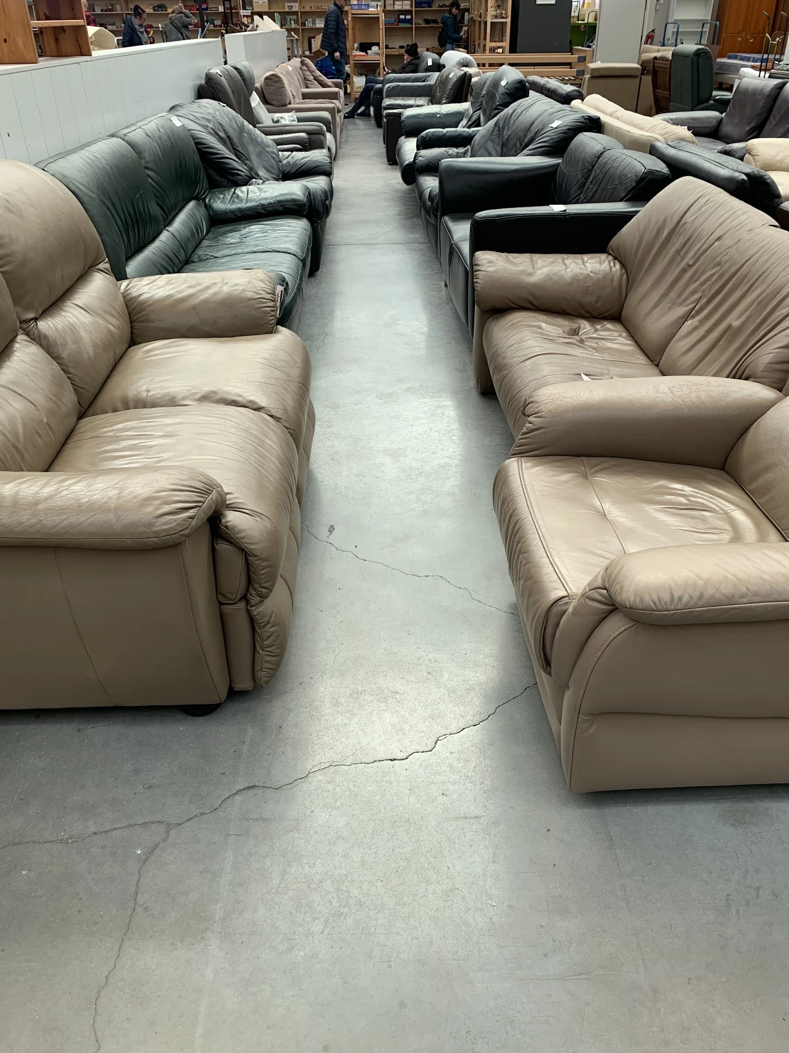 Beige lederen fauteuils op een rij in de winkel, met centrale doorgang ertussen