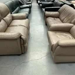 Beige lederen fauteuils op een rij in de winkel, met centrale doorgang ertussen