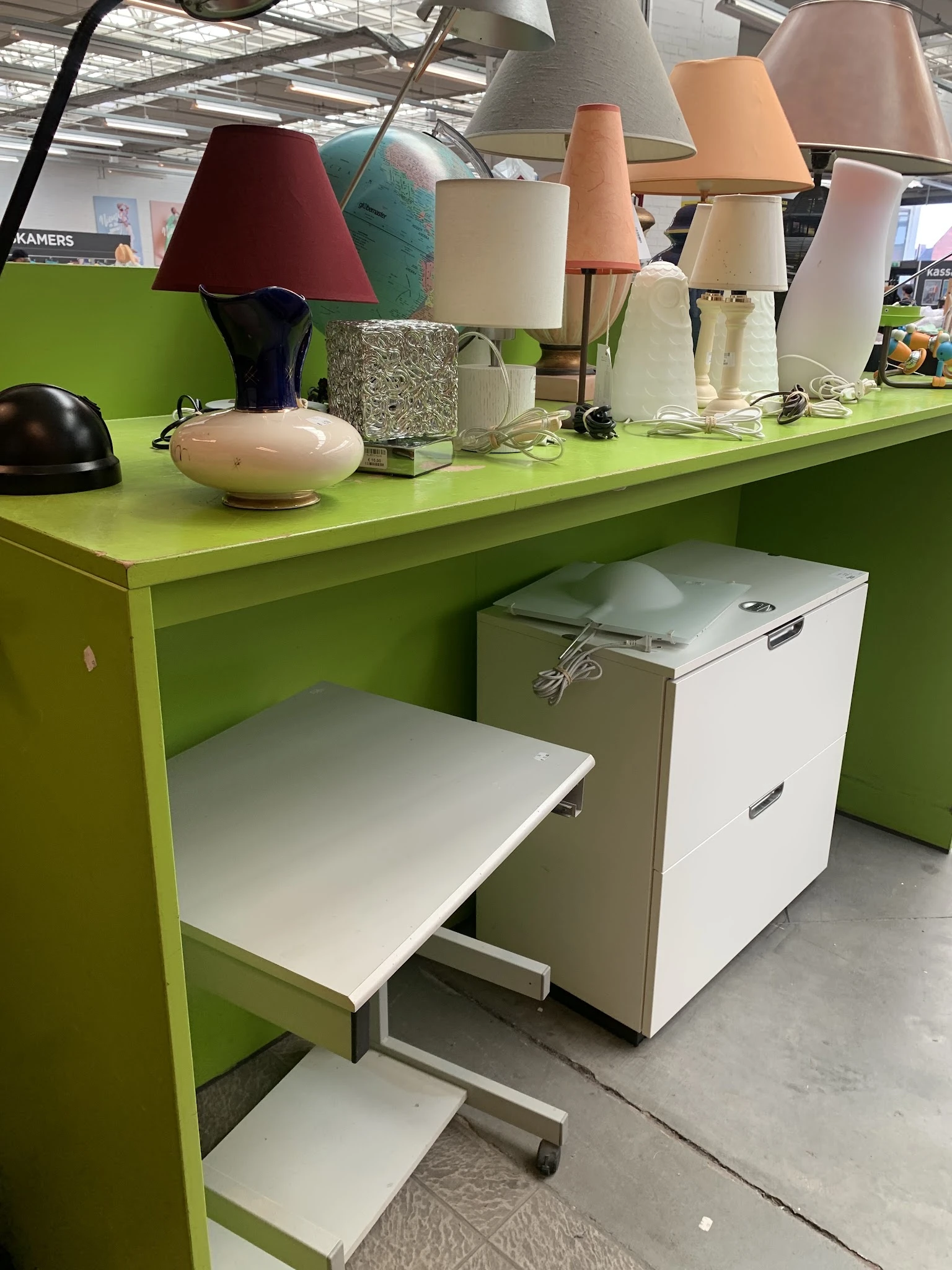 Groen bureau met witte laden en diverse huishoudartikelen op het blad