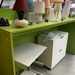 Groen bureau met witte laden en diverse huishoudartikelen op het blad