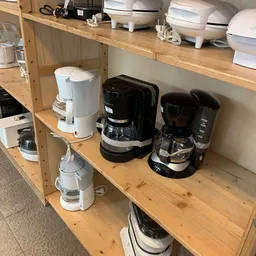 Verschillende koffiezetapparaten en waterkokers uitgestald op houten planken