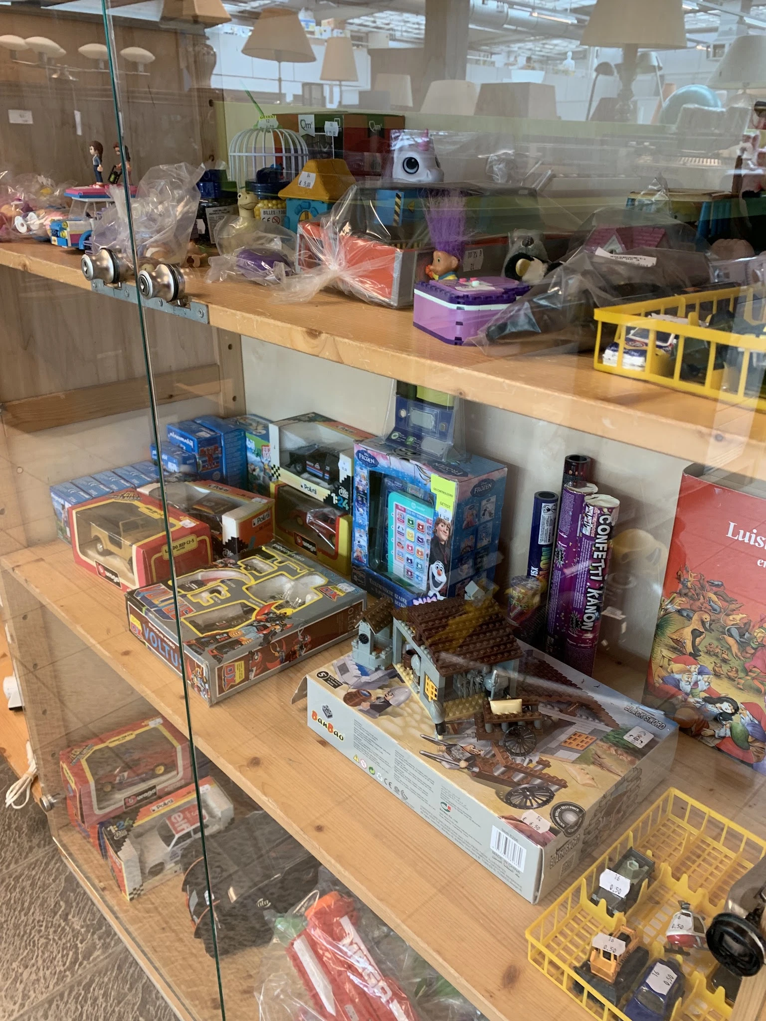 Vitrinekast met verzameling bordspellen, speelgoed en collectibles op houten stellage