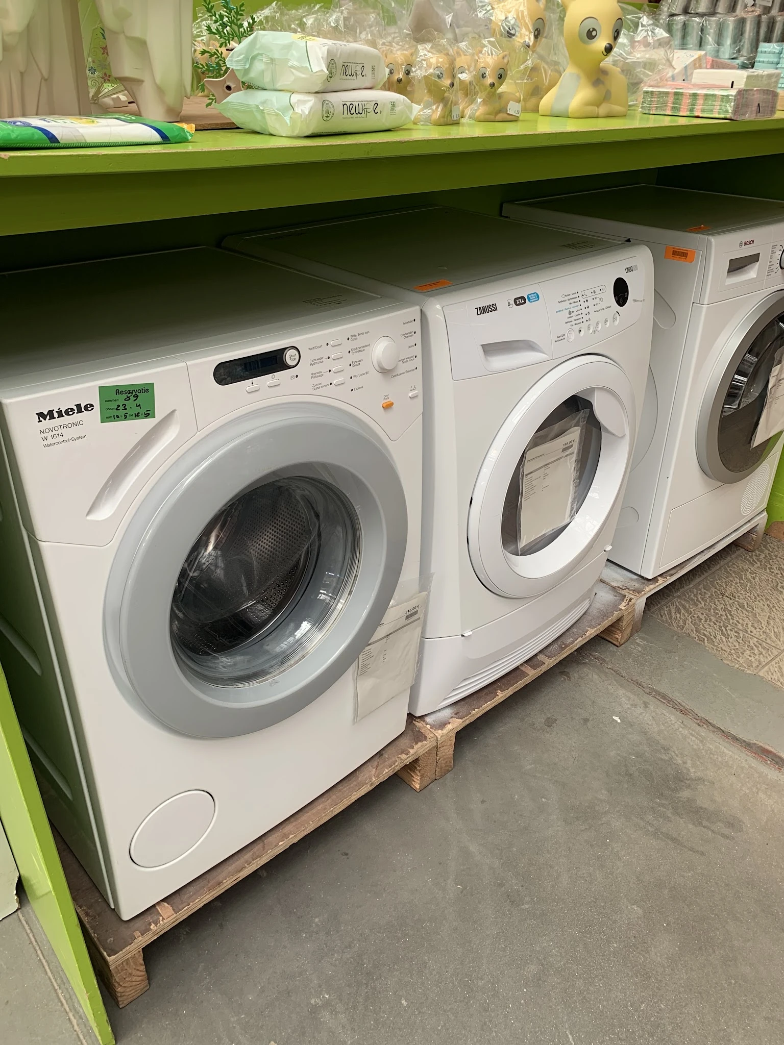 Drie witte wasmachines uitgestald naast elkaar in de kringloopwinkel