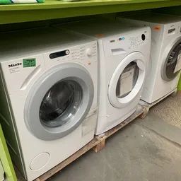 Drie witte wasmachines uitgestald naast elkaar in de kringloopwinkel