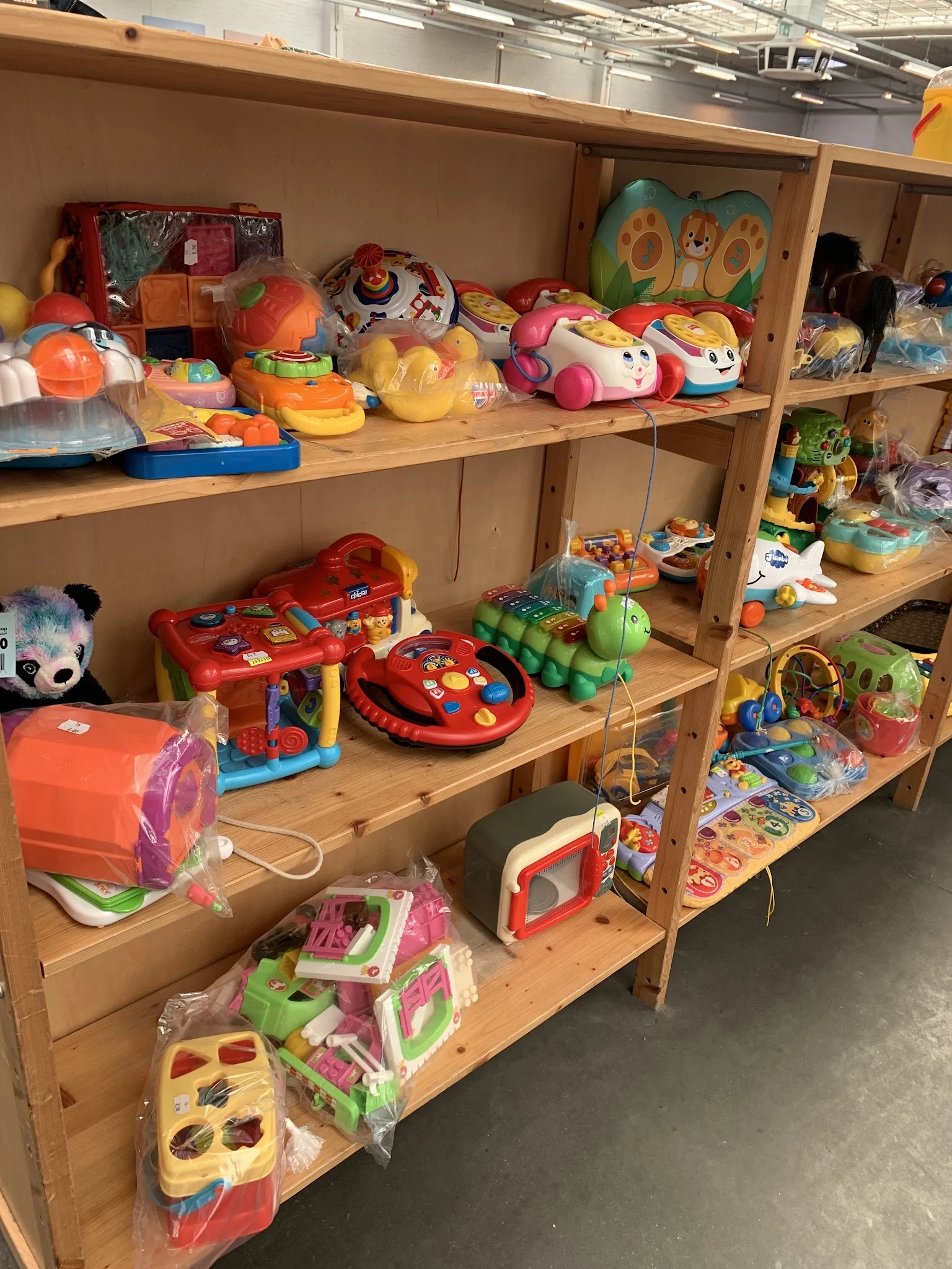 Houten stellingen met speelgoed: rode spelautomaten, gekleurde ballen, knuffelbeesten en verschillende kinderspeelgoed