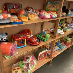Houten stellingen met speelgoed: rode spelautomaten, gekleurde ballen, knuffelbeesten en verschillende kinderspeelgoed