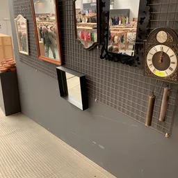 Winkelinterieur met grijze muur, zwarte tegeltjes, wandklok, spiegel en enkele decoratieve items