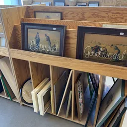 Uitgestalde tweedehands schilderijen en kunstwerken op een houten rek in de winkel
