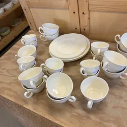 Verzameling witte porseleinen soepkommen en borden uitgestald op houten tafel