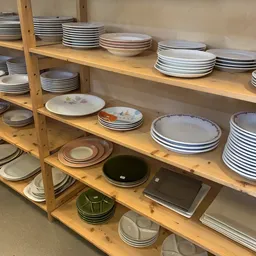 Houten stellingen met uitgestalde serviesgoed, borden en schalen in verschillende patronen en kleuren