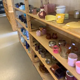 Houten stellingen met assortiment huishoudartikelen: glazen potten, bekers, kaarsen en serviesgoed