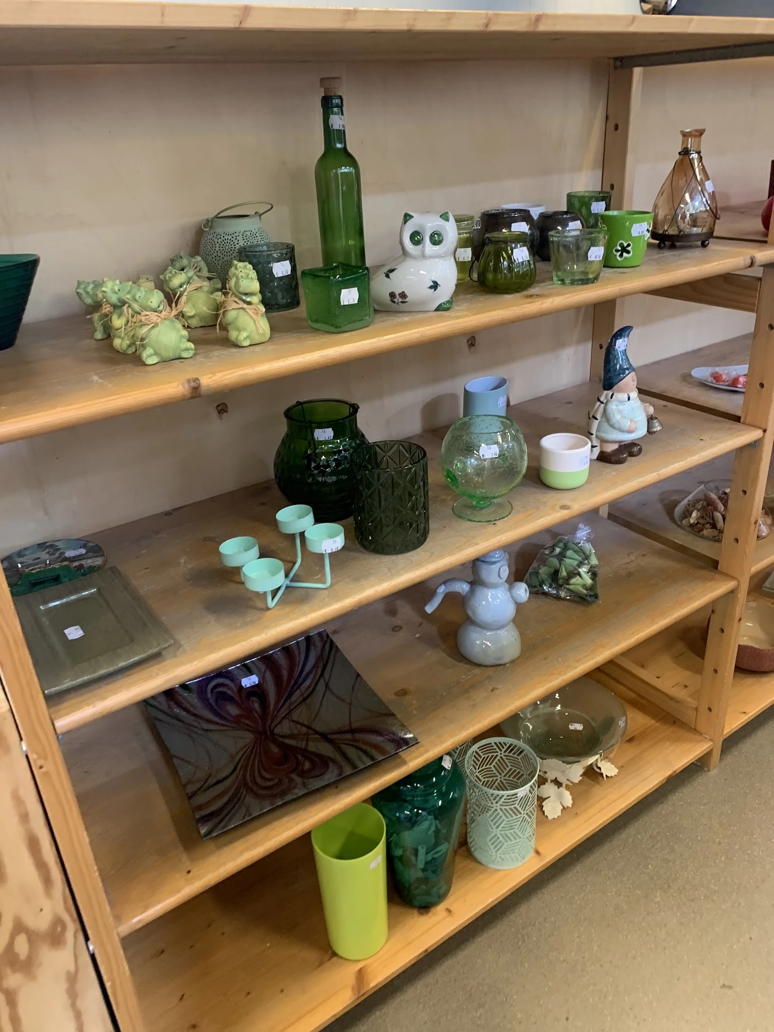 Houten stellingkast met diverse decoratieve artikelen: glazen potten, bloemen, keramische beeldjes en huishoudelijke spullen