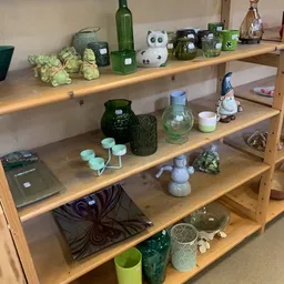 Houten stellingkast met diverse decoratieve artikelen: glazen potten, bloemen, keramische beeldjes en huishoudelijke spullen