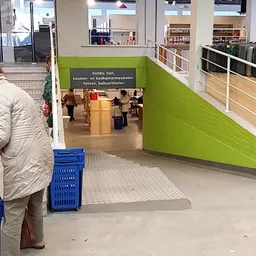 Ingang van de winkel met groene wand, bewegwijzering naar afdeling hobby, tuin en babyartikelen