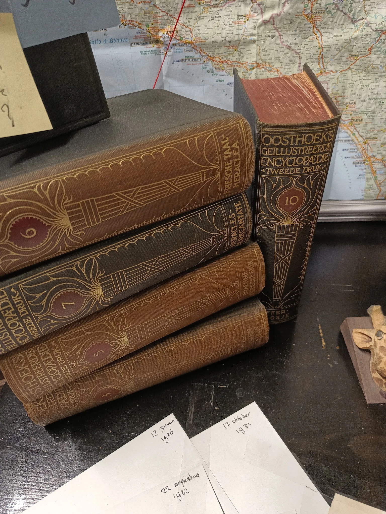 Stapel antieke boeken met leren inband en gouden decoratie, waaronder een Oosthoeks encyclopedie