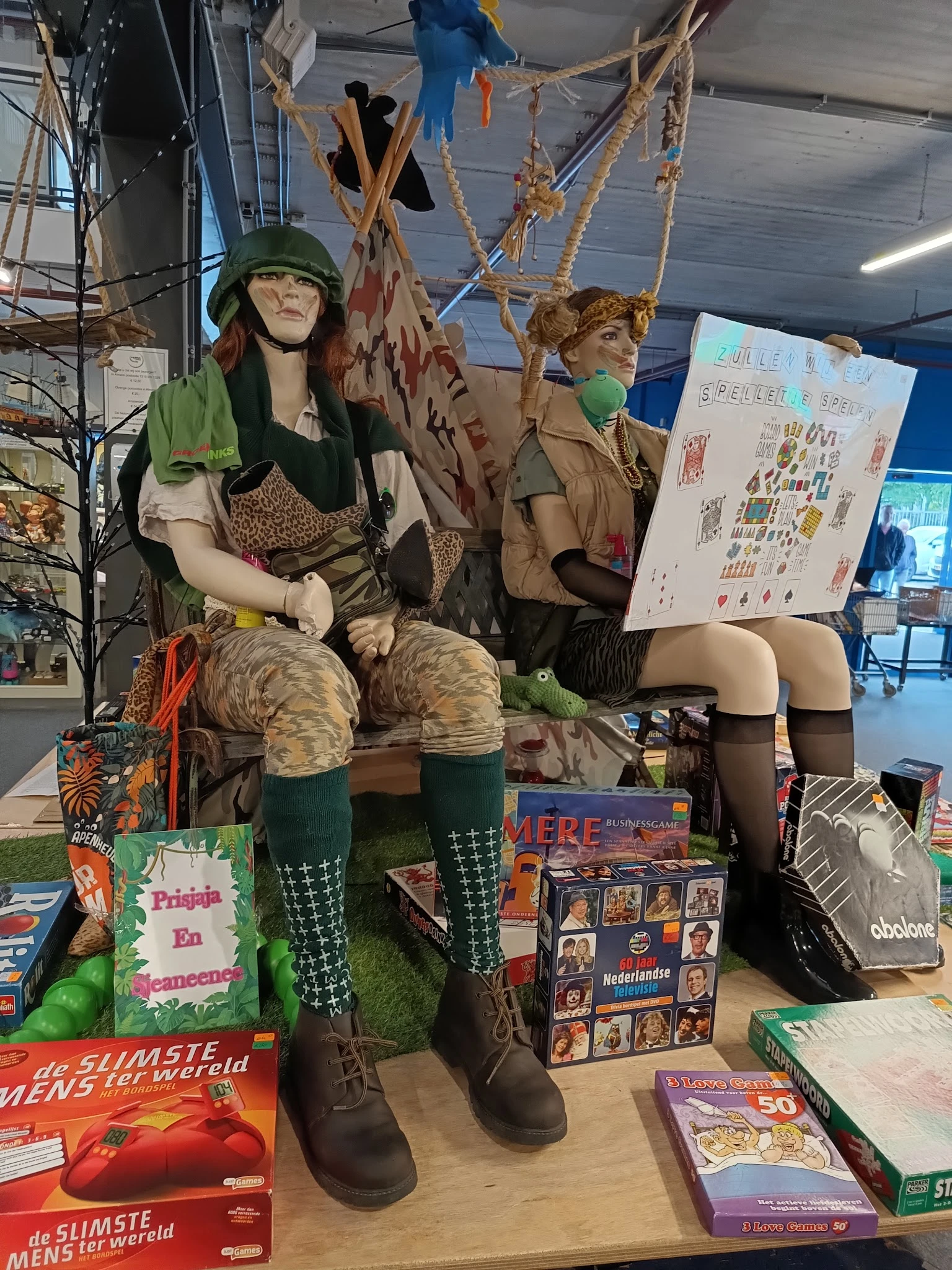 Etalage met poppen gekleed in vintage kleding en diverse tweedehands items zoals boeken en accessoires
