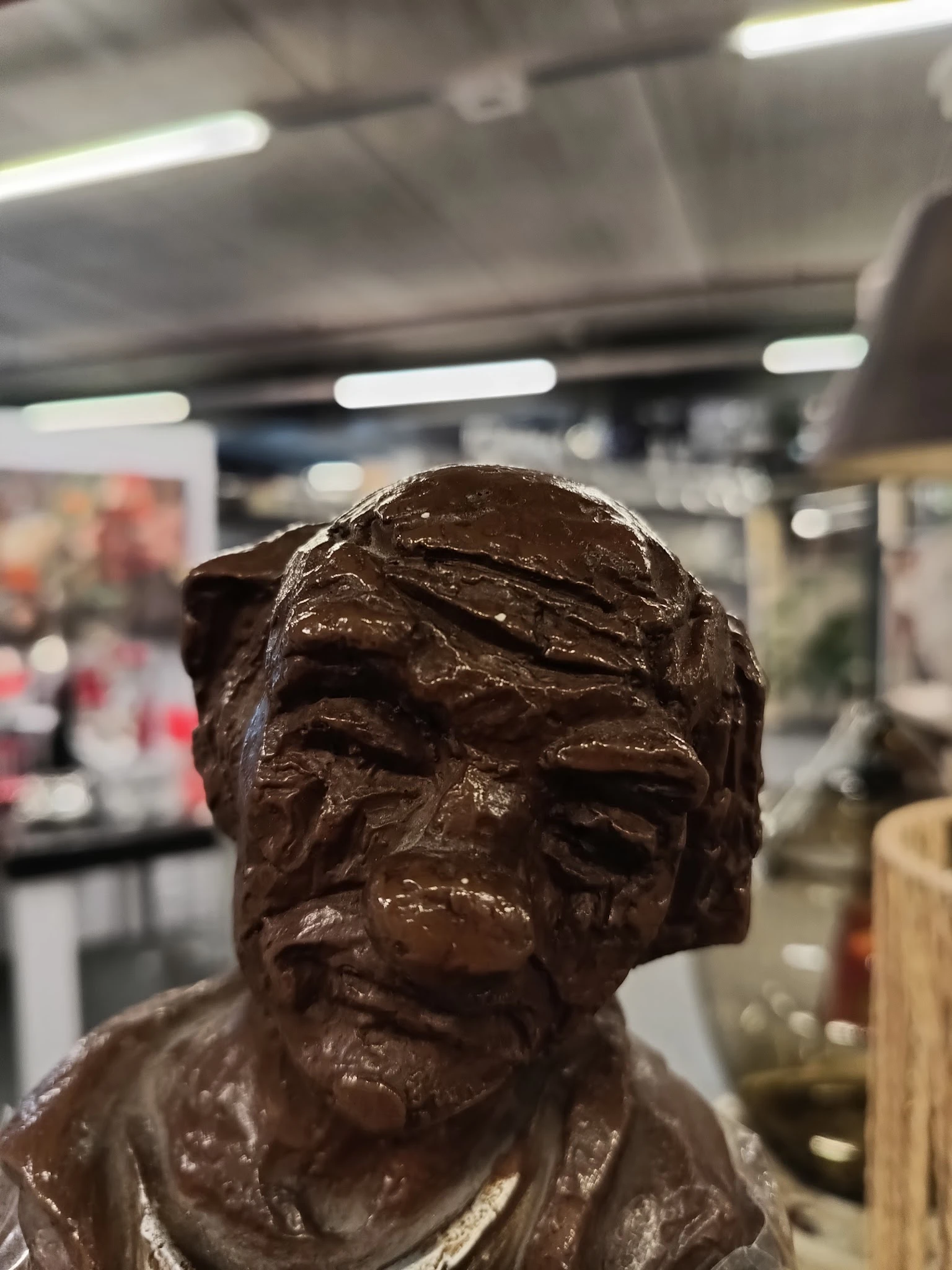 Close-up van een bronzen sculptuur van een mannelijk hoofd in een winkelomgeving