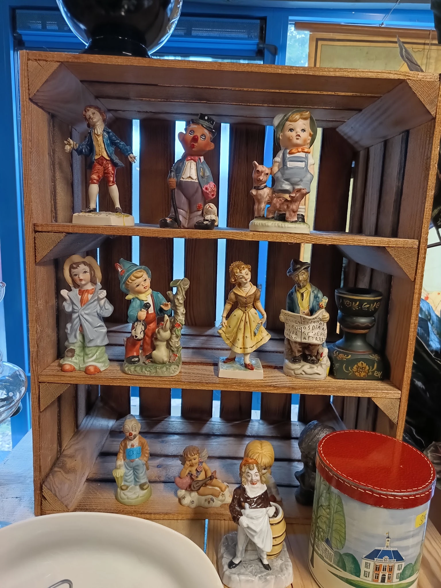 Houten vitrinekast met collectie antieke poppen en beeldjes op drie niveaus