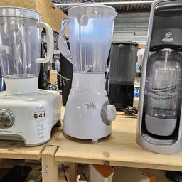Drie tweedehands blenders en keukenmachines op een werktafel in de winkel