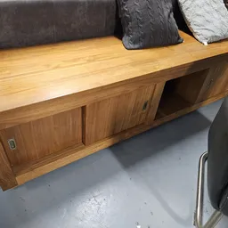 Houten dressoir of lowboard met deuren en open vak, tegen grijze bank met kussens