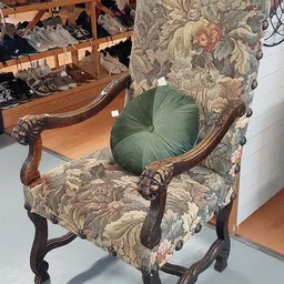 Antieke houten fauteuil met bloemenpatroon en groen fluwelen kussen