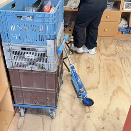 Winkelinterieur met blauwe plastic kratten en een blauwe step op een houten vloer