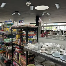 Winkelvloer met stellingen vol spullen, servies en huishoudartikelen, grote ramen met daglicht