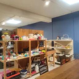 Houten stellingen met diverse spullen en huishoudartikelen in een kringloopwinkel