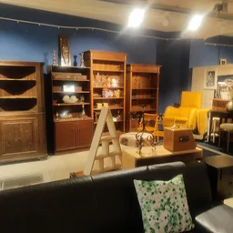 Winkelvloer met houten kasten, boekenrekken, gele stoelen en diverse meubels en decoraties