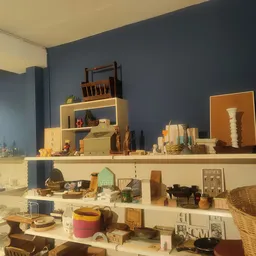 Planken met diverse huishoudelijke artikelen, decoratieve items, meubels en accessoires in een kringloopwinkel