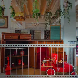 Speelhoek in kringloopwinkel met rode vintage speelgoedauto's achter hek, hangplanten aan plafond