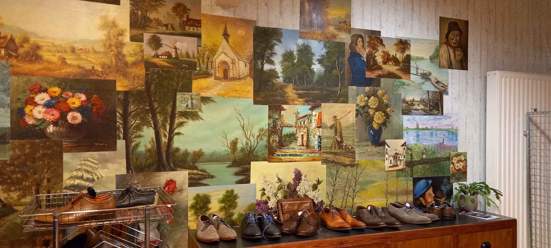 Winkeldisplay met schilderijen aan muur en schoenen op houten schouw