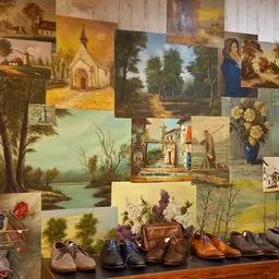 Winkeldisplay met schilderijen aan muur en schoenen op houten schouw