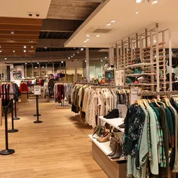 Ruim winkelinterieur met kledingrekken en displays, houten vloer en moderne verlichting