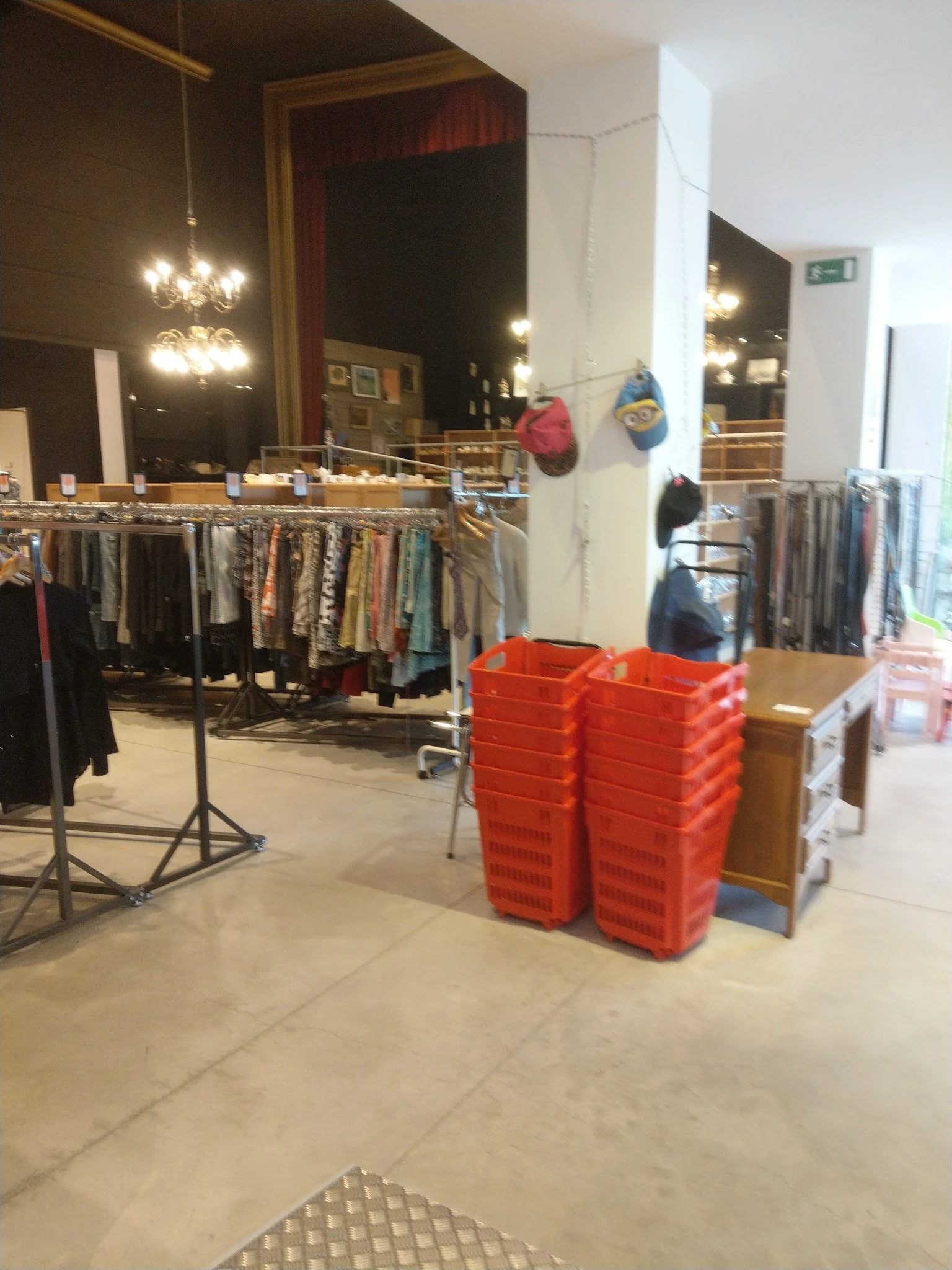 Winkelinterieur met kledingrekken en rode plastic kratten op de vloer
