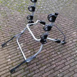 Witte fietsendrager met zwarte bevestigingsklemmen op bakstenen ondergrond