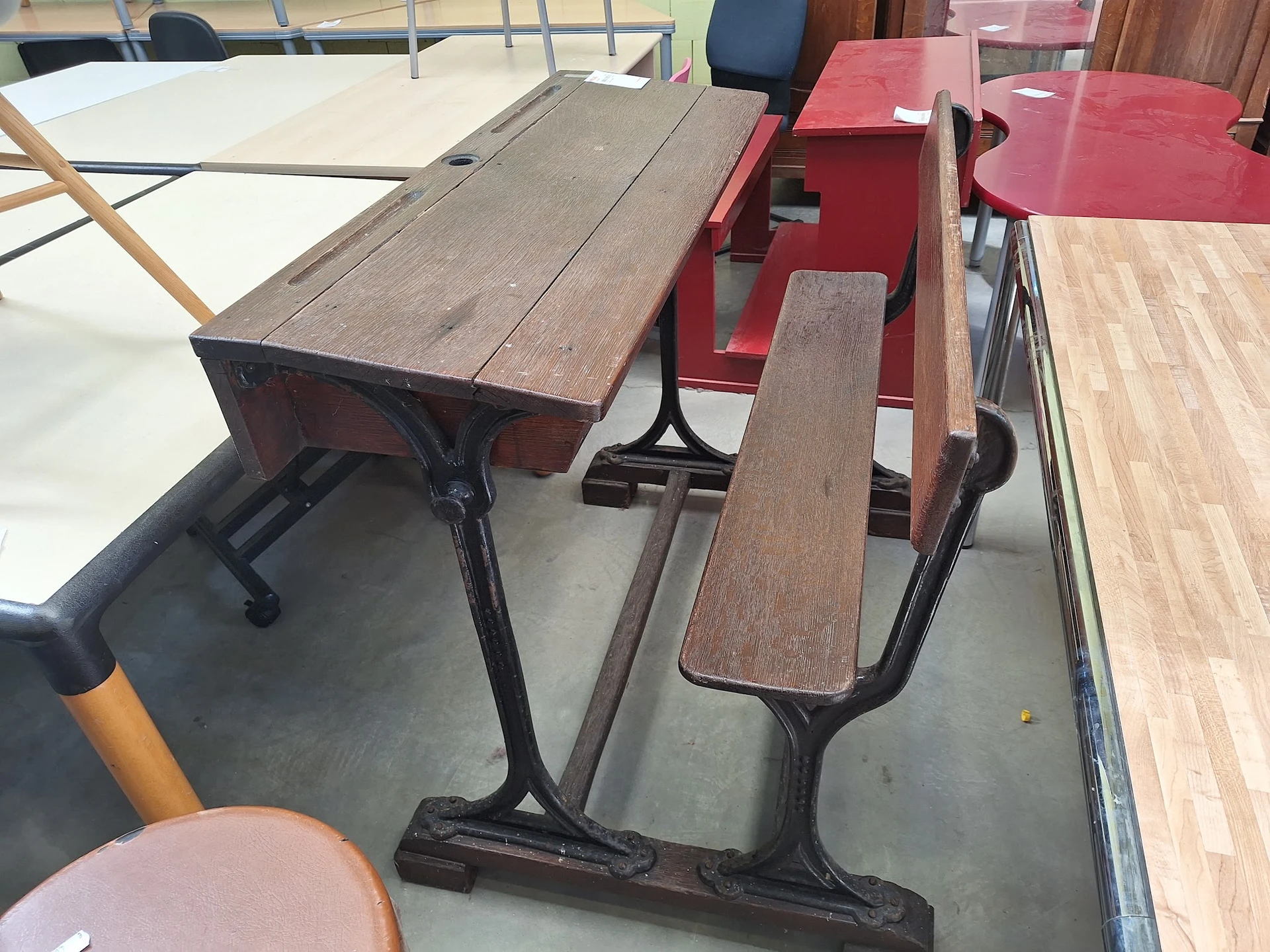 Tweedehands schoolbanken en stoelen met houten zittingen en zwarte metalen onderstellen in de winkel